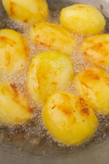 Golden potatoes are fried in boiling oil in a cauldron