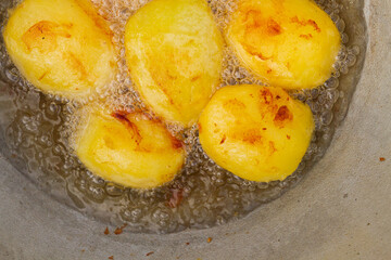 Golden potatoes are fried in boiling oil in a cauldron