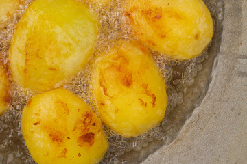 Golden potatoes are fried in boiling oil in a cauldron