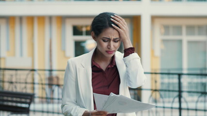 Fototapeta premium Sad businesswoman feeling upset with project data outdoors, Lady reading papers