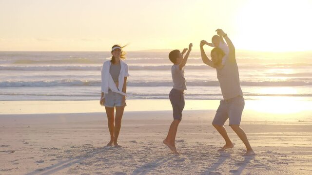 Happy family playing and having fun on the beach at sunset. Slow Motion. Family, Freedom and Travel concept.