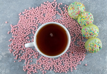 Round cookies with green cream frosting and cup of tea
