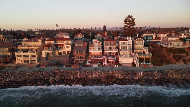 4K Aerial view drone shot of City Beach coastline in South California with the blue Pacific Ocean with waves coming in and beach with nice houses on the background at the beautiful Sunset