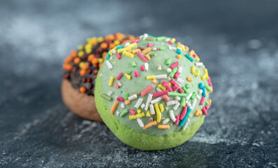 Two colorful cookies with sprinkles on marble background