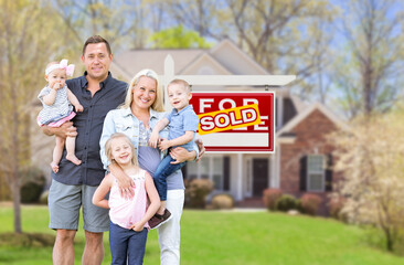 Fototapeta premium Happy Young Caucasian Family Outside In Front of Their New Home and Sold Real Estate Sign