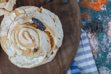 Fried meringue cookie with black raisines on a wooden board