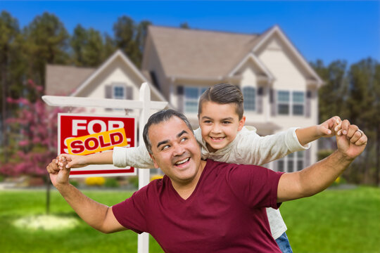 Hispanic Father and Mixed Race Son Having Fun In Front of House and Sold Real Estate Sign