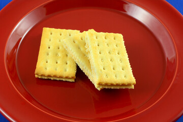 Cracker sandwich with tomato basil cheese filling on red plate