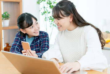 Obraz premium スマートフォンを見る娘とパソコンをする母