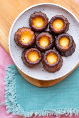 A close up of Canelés de Bordeaux on wood with a turquoise napkin