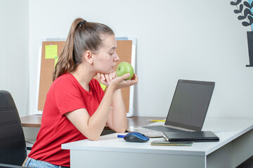Female employee having a green apple in the office