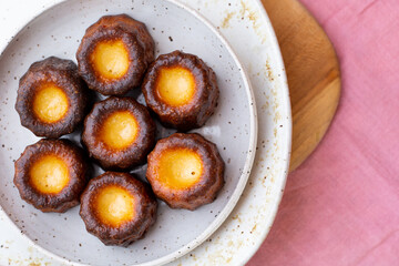 Canelés de Bordeaux on a white plate and pink tablecloth from above