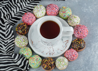 Tasty glazed cookies and cup of tea on marble background