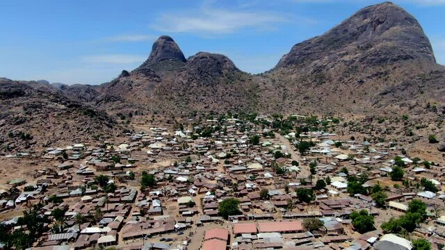 The Nigerian city of Dass beneath the rugged mountains of the Bauchi State - push forward aerial view