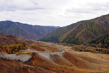The mountain road serpentine descends from the cliff into a picturesque autumn valley.