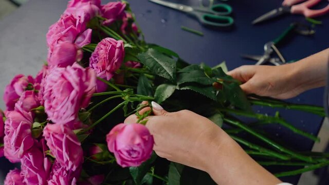 The master prepares a wedding bouquet of pink roses. Young florist assembles a perfect pink rose bouquet