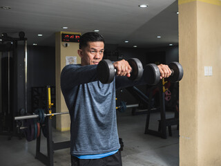 A Filipino fitness model doing front dumbbell raises.