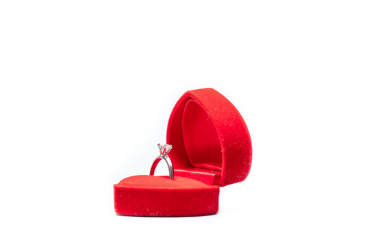 Diamond ring in a red heart shaped jewellery box on white background.