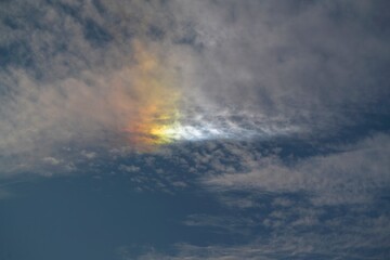 This image showcases a beautiful, vibrant rainbow peaking through a cloudy sky.