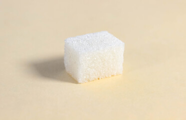 One rectangular sugar cube on a beige background.