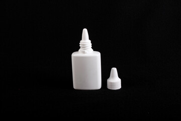 nasal drops white plastic  bottle, black background, cap off