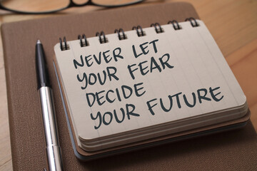 Never let your fear decide your future, text words typography written on book against wooden background, life and business motivational inspirational