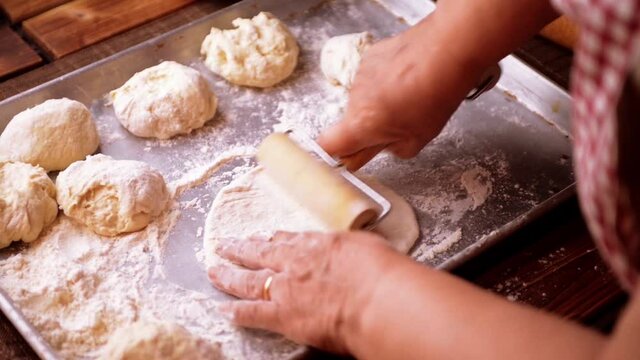Dough flattened with rolling pin stretched for pizza or calzone by senior chef