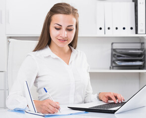 Young office worker is working with documents and laptop in the office.