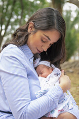 retrato joven mama con bebe al aire libre en parque día de la madre