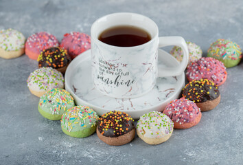 Tasty glazed cookies around cup of tea