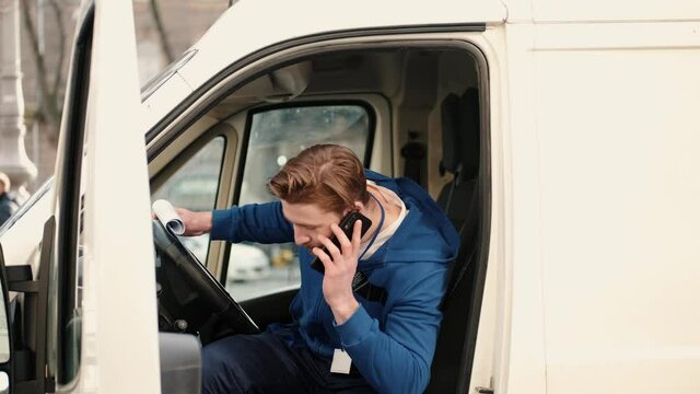 Delivery service man sitting in van and writing documents on clipboard before delivering a package to customer. Checking list, working process.
