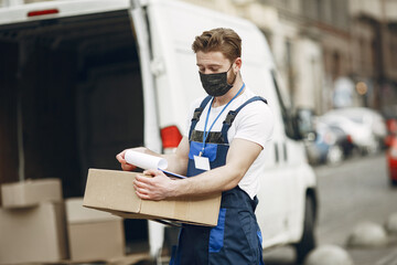 Man by the truck. Guy in a delivery uniform. Man in a medical mask. Coronavirus concept.