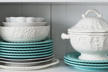 A stack of white and turquoise dishes in a cupboard