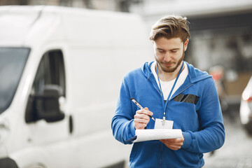 Man by the truck. Guy in a delivery uniform. Man with clipboard.