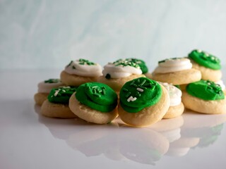 St Patrick’s Day holiday frosted sugar cookies with green and white frosting and sprinkles with four leaf clover shamrocks for a festive sweet treat.