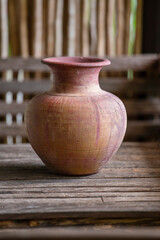 Fototapeta na wymiar Old clay vase of manual work on wooden table in thai home