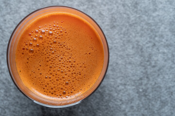 Glass of fresh carrot juice background, top view, close up