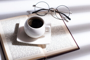 Obraz na płótnie Canvas cup of coffee with book and glasses