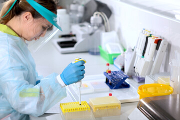 Laboratory assistant in the clinical and diagnostic laboratory. The person is out of focus. Hands in protective gloves. Concept of healthcare. Testing and development of the vaccine.