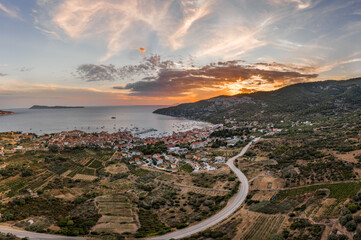 Aerial drone shot of Komiza town with sunset burning sky on Vis Island in Croatia summer