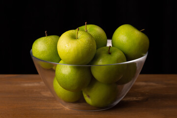 ripe green apples in a transparent bowl, close up
