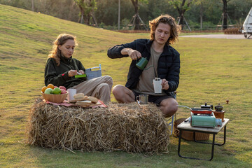  Boyfriend and girlfriend eating green apples, fruit for breakfast in front of tent during holiday camp.
