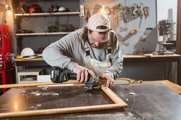Male carpenter working on old wood in a retro vintage workshop.