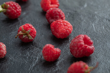 Pile of red raspberries on black background
