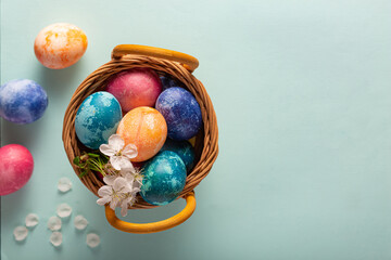 Easter eggs in a basket on a blue background, top view