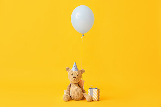Air balloon with teddy bear and gift on color background