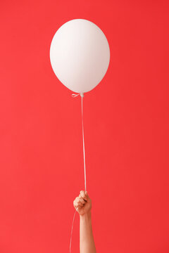 Human Hand With Air Balloon On Color Background