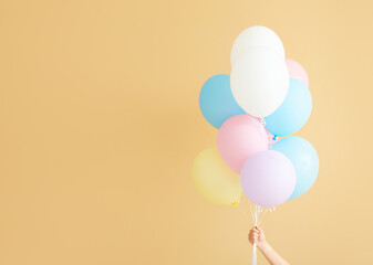 Human hand with air balloons on color background