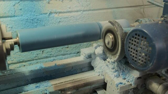 Processing of a polyurethane shaft on a milling equipment. The blue polyurethane roller is milled. Milling work for the production of the required size of parts 