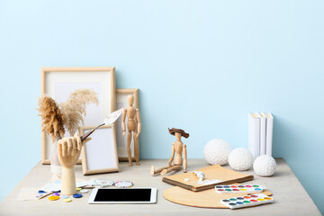 Creative composition with wooden mannequins and artist supplies on table